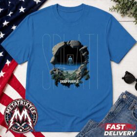 A blue deep purple splat shirt laid flat next to jeans and an american flag, showing a graphic of a rock cave opening.