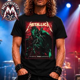A man with long curly hair wearing the Metallica M72 Budapest Pop-Up Poster Art By Alex Almeida For June 11th And 13th At Puskas Arena In Hungary Short T-Shirt while standing on a stage with concert lights. The graphic on the black tee features a glowing green demonic horse and a skeletal rider under lightning bolts with the classic Metallica logo across the top.